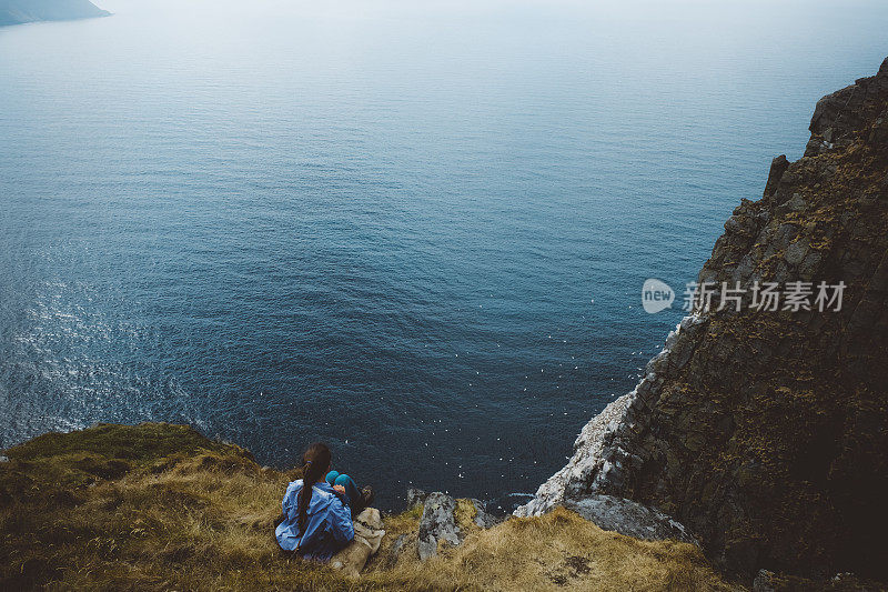 在挪威徒步旅行和看海后带着狗休息的女人