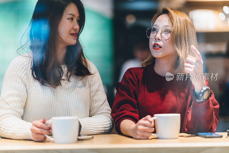 两个亚洲女性朋友在咖啡馆聊天