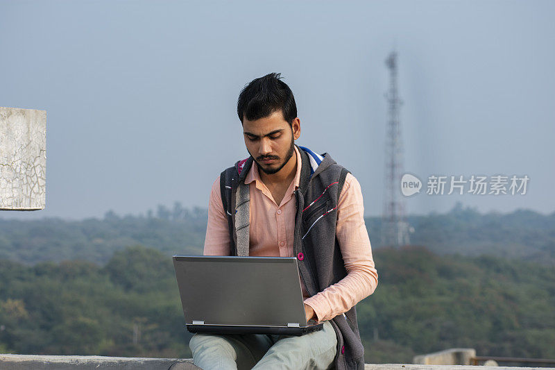 一个印度年轻人在用笔记本电脑工作