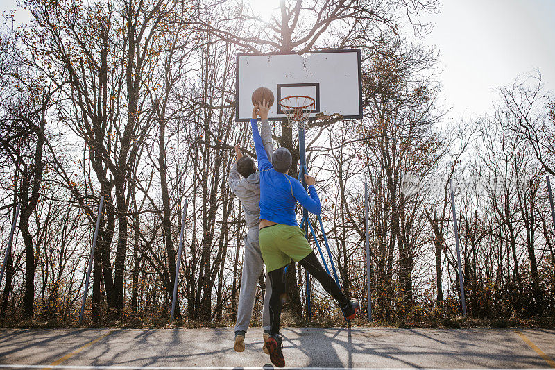 两个篮球运动员在户外的院子里玩