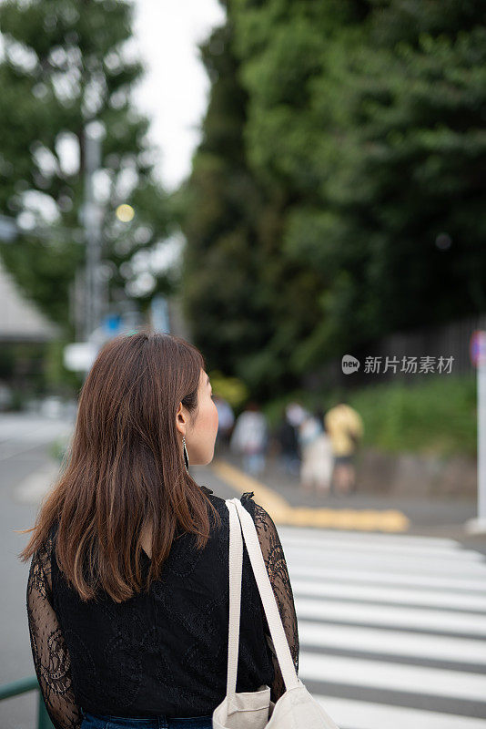 一名女子走在原宿车站附近的街道上，原宿是日本著名的观光胜地