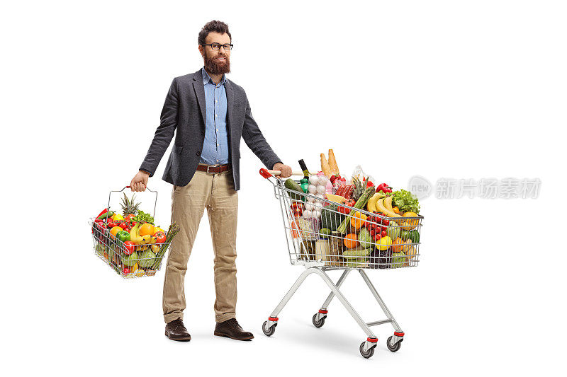 一个年轻人推着购物车和一个装着水果和蔬菜的购物篮站着