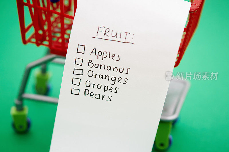 在绿色背景的小超市手推车水果购物清单