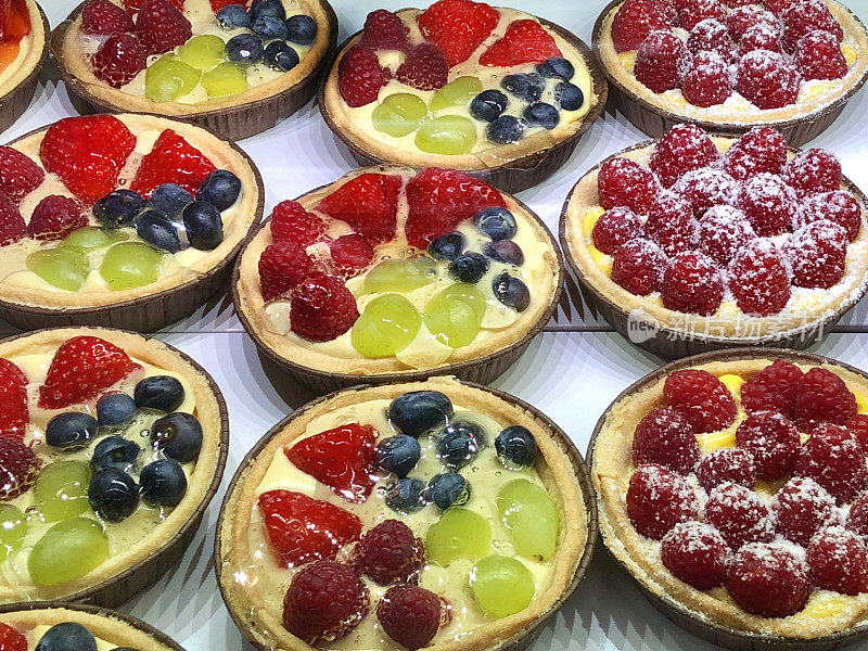 图片中有草莓、蓝莓、绿葡萄和覆盆子的法式蛋挞，带有酥皮馅饼的咖啡厅蛋挞，涂有草莓和浆果片的奶油蛋挞，糖霜，夏季布丁