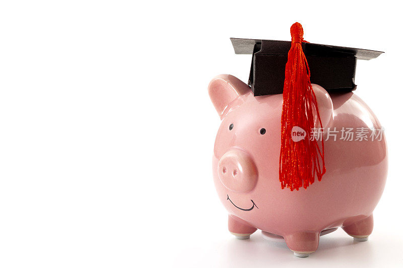 大学教育成本，学费资助，大学毕业生经济成本概念主题与近距离戴着小猪储蓄罐毕业帽孤立在白色背景与文案空间