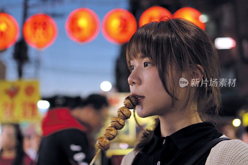 年轻女子在夜市享受美食