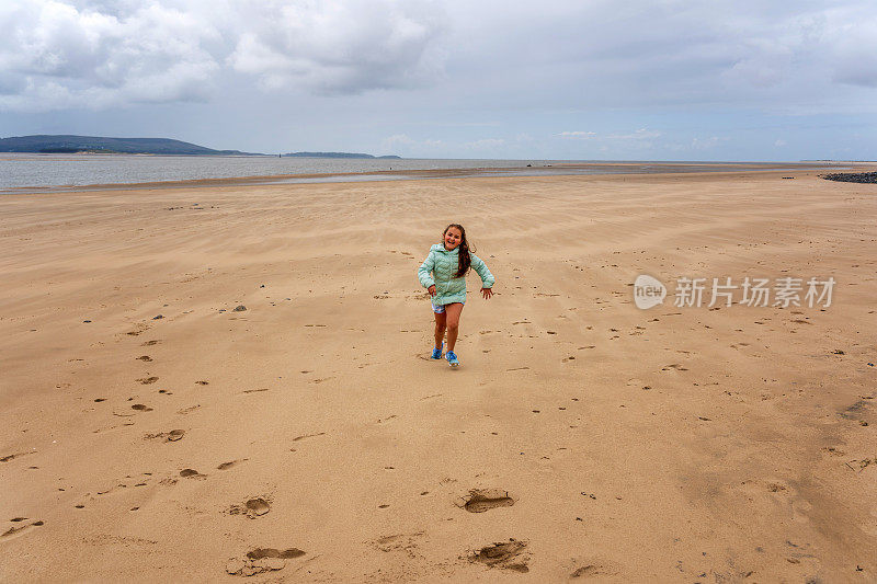 11岁的小女孩在威尔士海滩上跑步