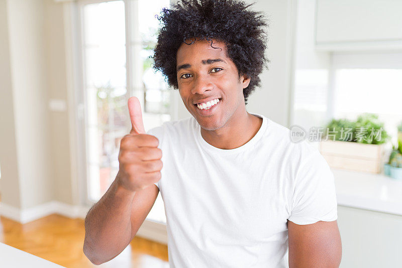 非裔美国人穿着白色t恤做快乐的拇指手势与手。赞许的表情看着镜头，表示成功。
