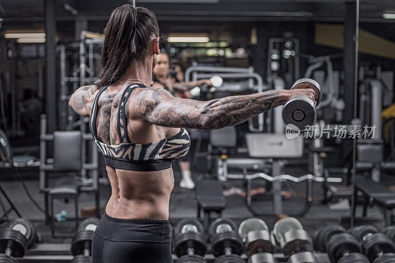 纹身的高级女性在健身房锻炼