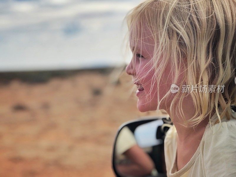 年轻的金发女孩探出车窗在沙漠微笑