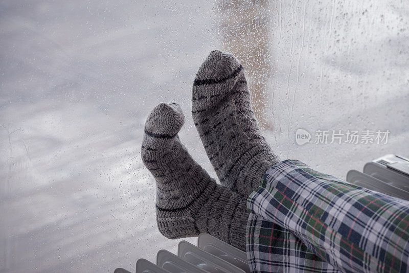 近距离图像的女人的脚散热器加热器在降雨的冬季。