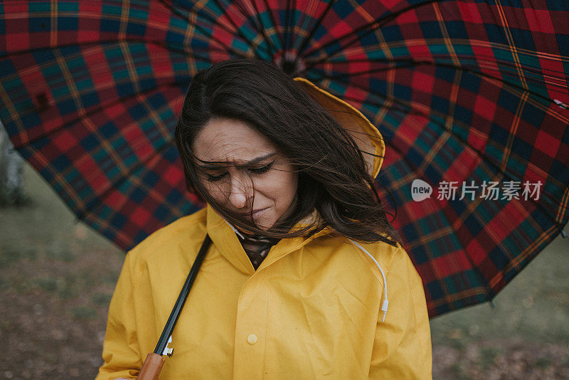 穿着黄色雨衣的年轻女子在公园里度过雨天