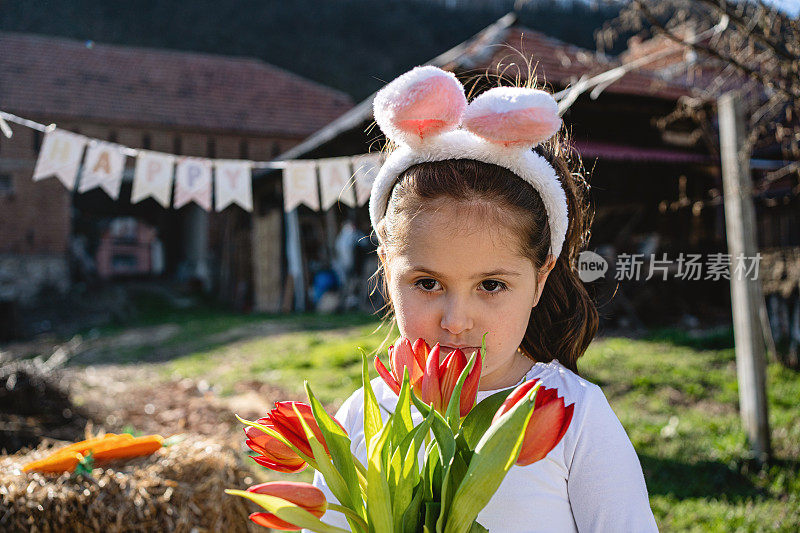 美丽宁静的孩子拿着郁金香，戴着兔子耳朵在复活节