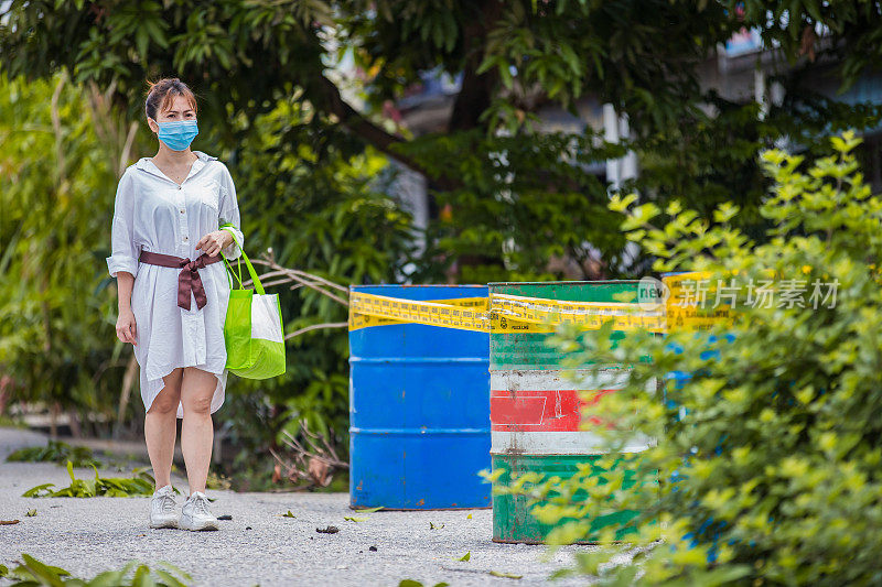 一名亚洲妇女在冠状病毒封锁期间戴着防毒面具外出购物。她绕过了警戒线的边界