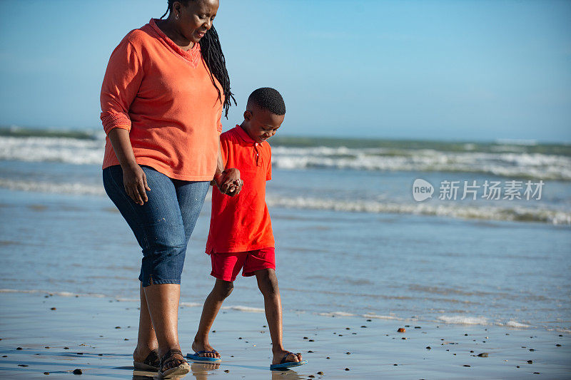 男孩光着脚和奶奶在海滩上走得更近了