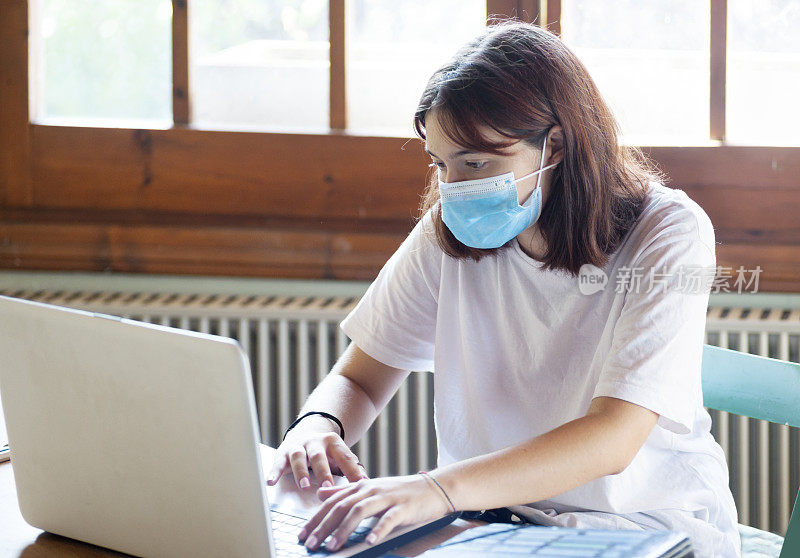 带着笔记本和口罩学习的女孩