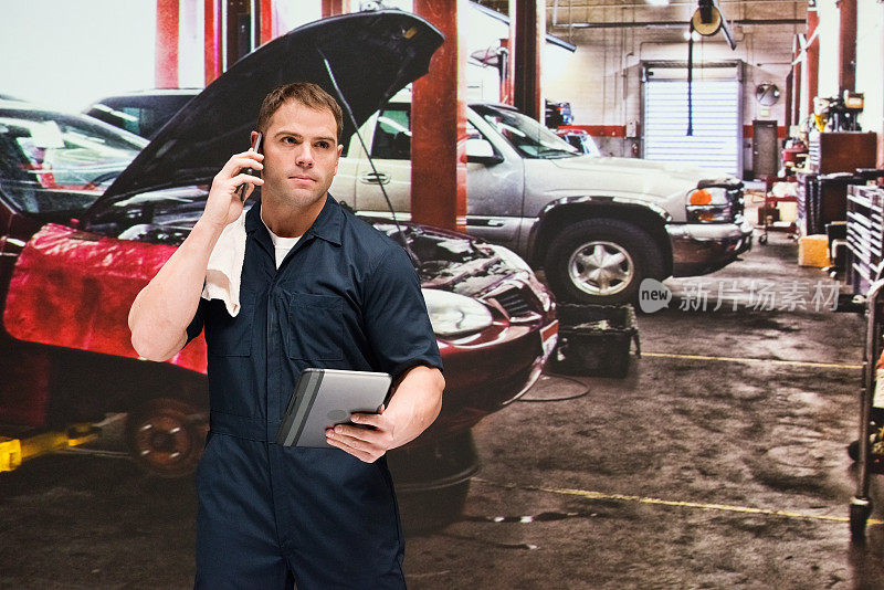 白人年轻男性修理工在汽车修理店修理穿着工作服和使用智能手机
