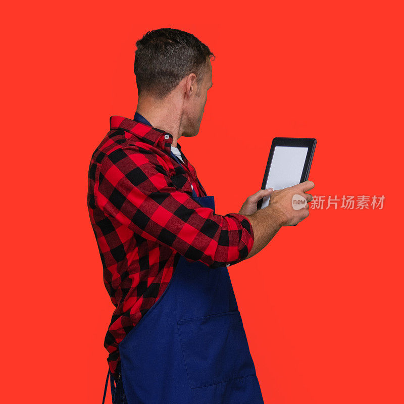 白人年轻男性站在有色背景下穿着伐木工人衬衫使用触摸屏