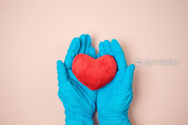 双手在蓝色的医疗手套持有心脏形状。感谢新冠肺炎大流行期间的医生和医务工作者。
