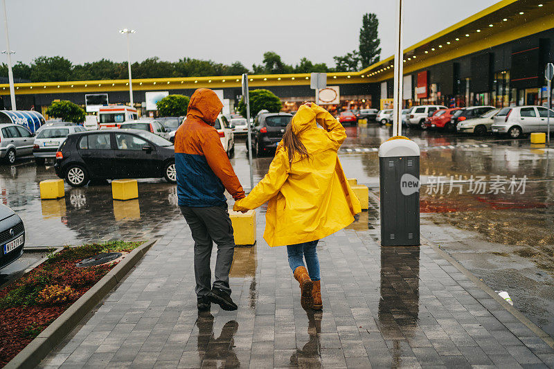 一对快乐的情侣在雨天在城市里跑步