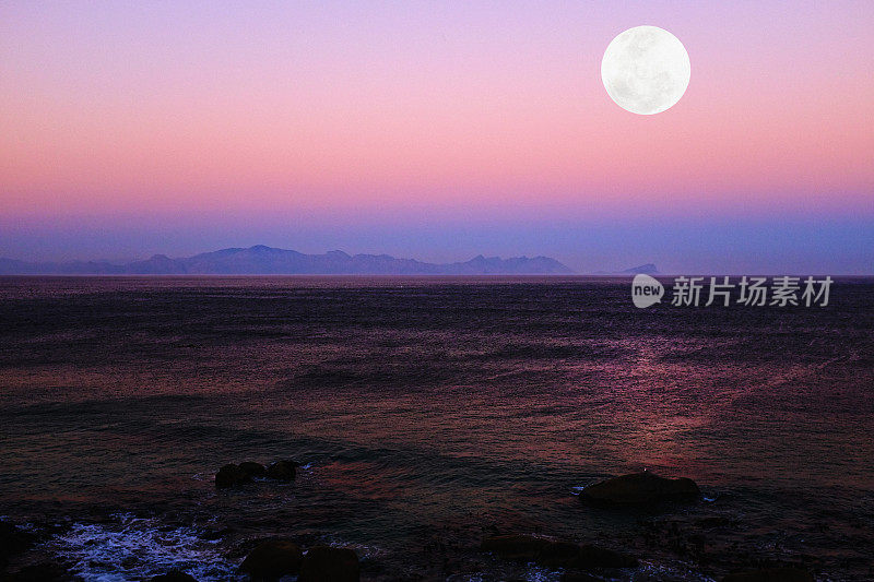 月亮升起在岩石海岸美丽的海面上