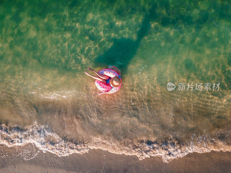 女人游泳和漂浮在海边的水与甜甜圈浮动鸟瞰图