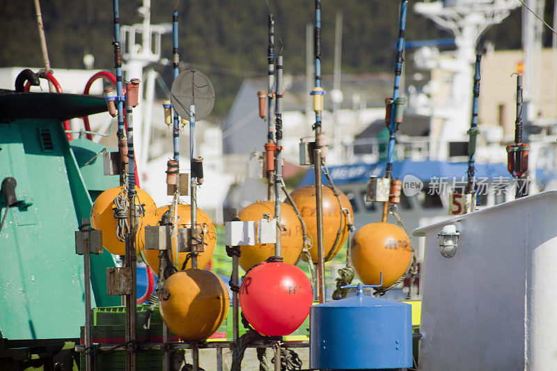 渔船系泊，甲板上有渔钩和彩色浮标。
