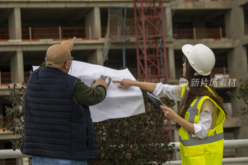 在建筑工地，工人们拿着平板电脑