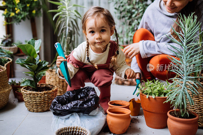 可爱的女孩和妈妈在房子阳台上种花