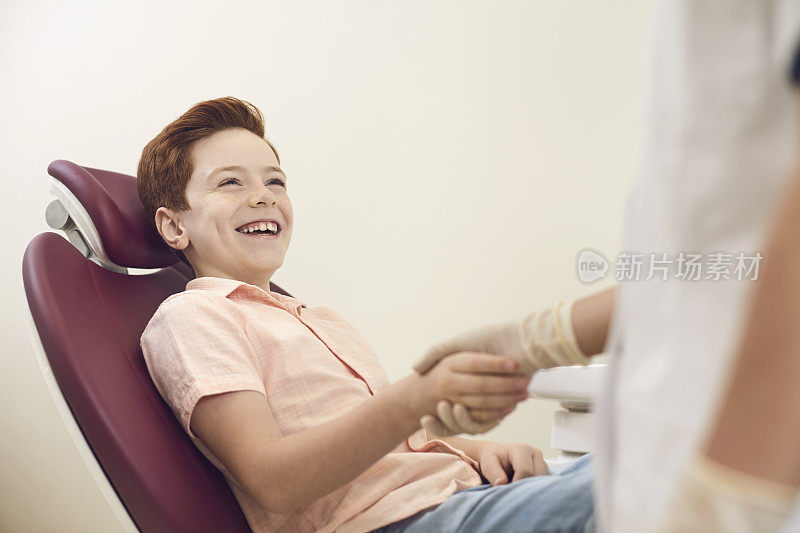 小病人在诊所接受牙科治疗后，与牙医握手。