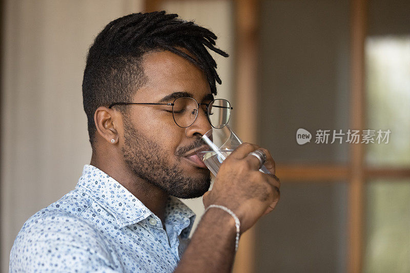 近距离观察口渴的非洲裔美国人戴着眼镜喝水