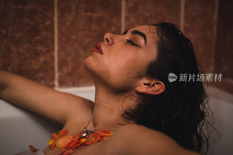 一个年轻，异国情调和强壮的女人坐在浴缸里，她的头发在背后