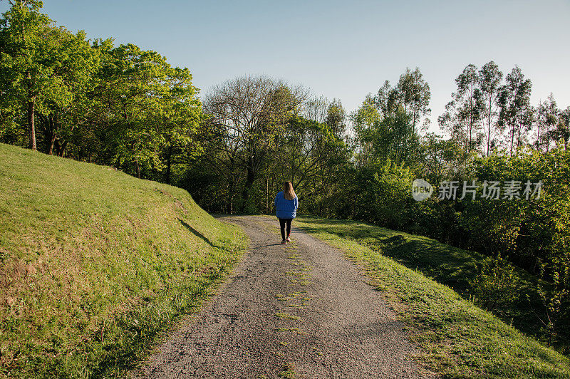 一个年轻女子走在森林里的路上