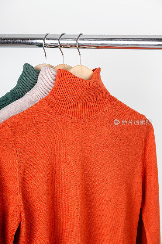 衣架上的空白高领毛衣模型。明亮的橙赭色卷领与米色和绿色。在最小的内部平原上模拟。