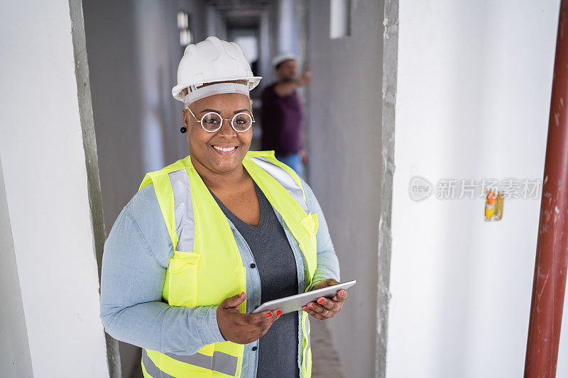 一名女性建筑工人在建筑工地使用数码平板电脑