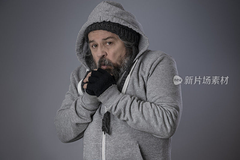 一个无家可归的人搓着双手取暖。
