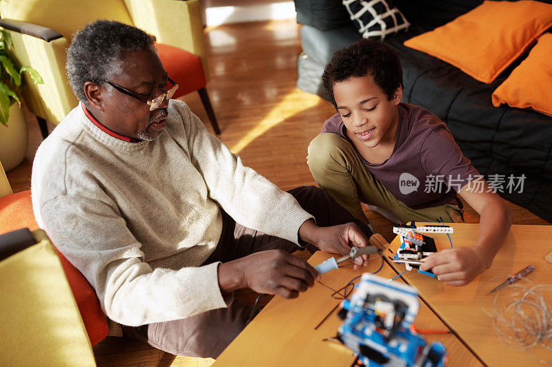 一对爷爷和孙子在家里一起制作机器人。机器人和电子教育。