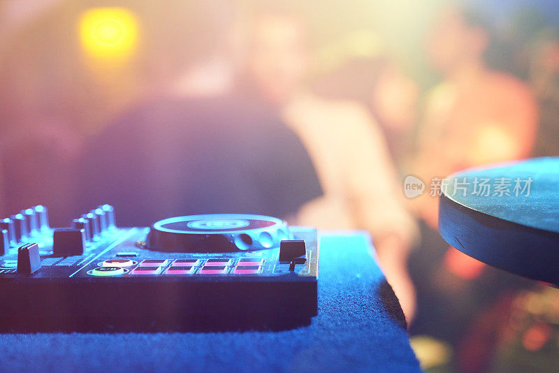 在一个俱乐部的派对上，无法辨认的男性DJ在转盘上播放音乐的特写。