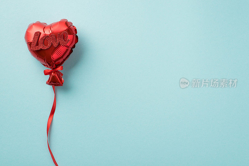 俯视图照片的情人节装饰红色心形气球与丝带和题字爱在孤立的柔和的蓝色背景copyspace