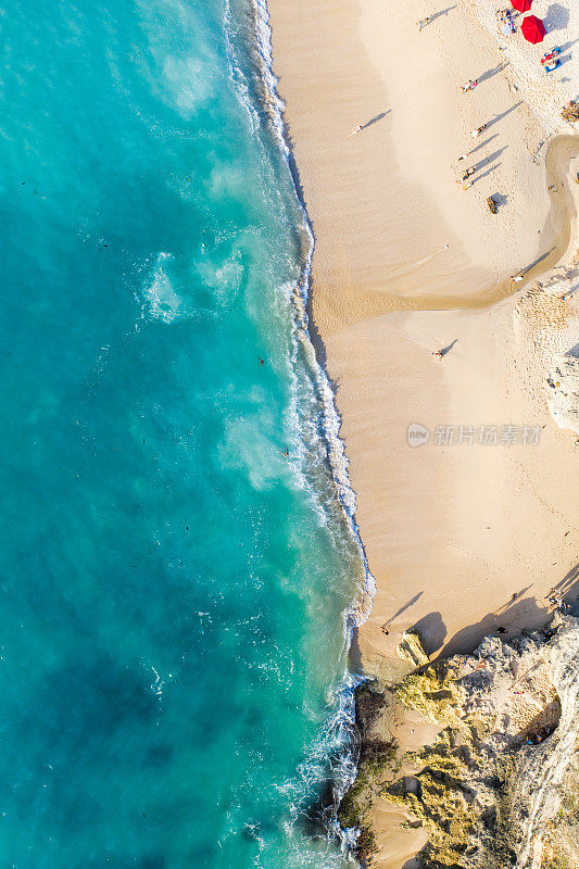 从上面的海滩场景——蓝色的海浪拍打着沙滩。