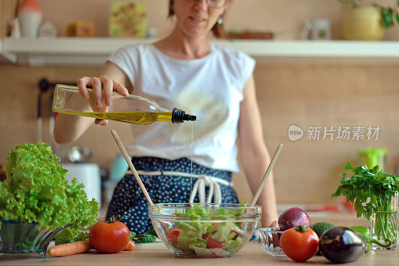 快乐的女性在家庭厨房准备健康的沙拉。吃健康的饮食