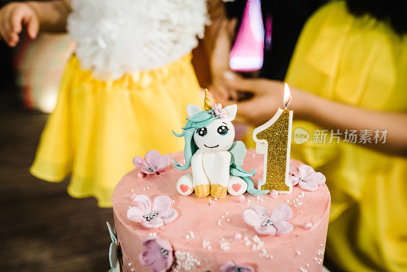 一年的生日蛋糕。蛋糕上装饰着独角兽、蜡烛和鲜花。节日甜点的概念。