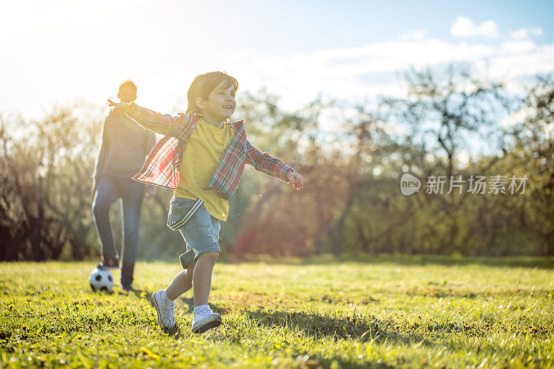 日落时分，男孩在公园里伸开双臂奔跑