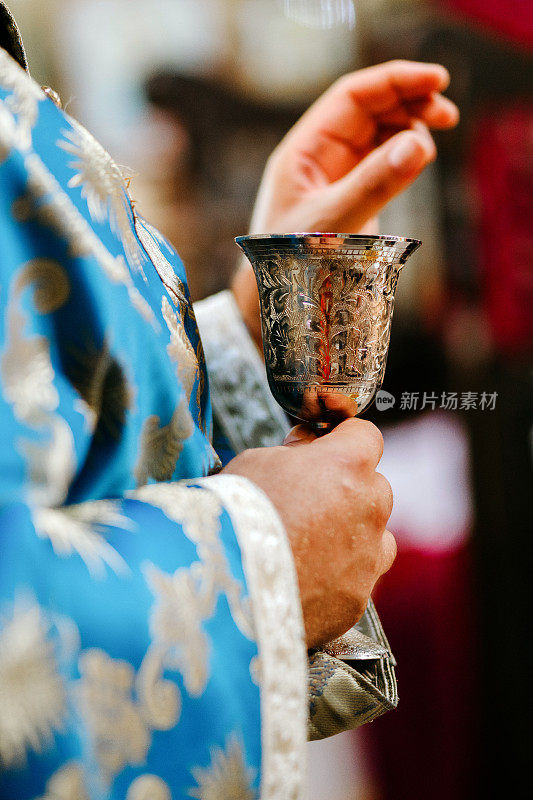 在东正教举行的婚礼仪式上，牧师的手和盛有酒的婚礼礼杯