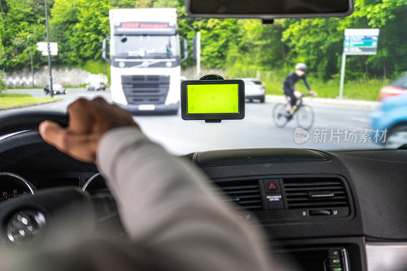 一名男子驾驶车窗上装有GPS导航仪的汽车