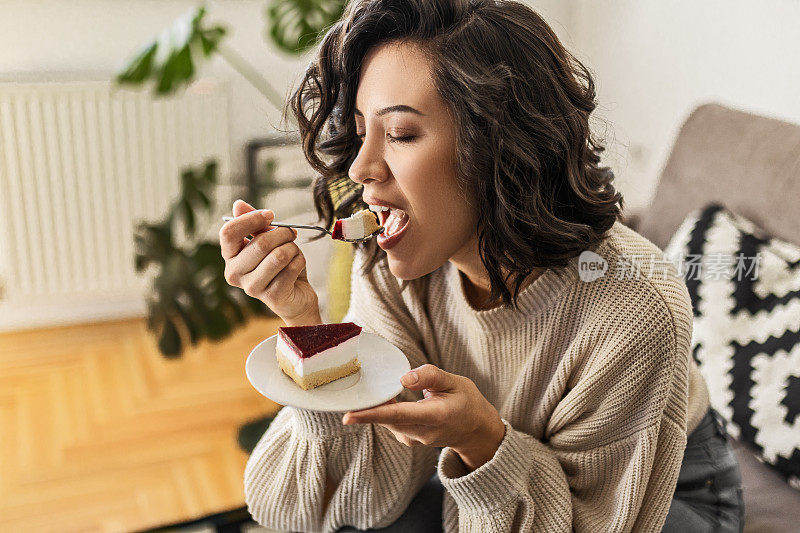 年轻的女人正坐在客厅里吃蛋糕