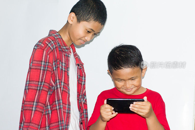 两个小男孩使用孤立的白色背景手机