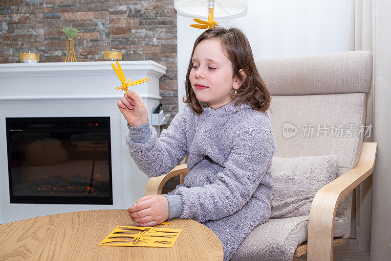 一个女孩，一个7岁的白人孩子，用木制的构造器组装了一只蜻蜓，并为她的成功而高兴。
