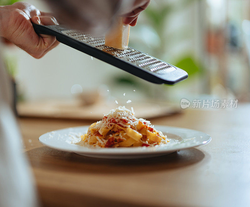 男子用新鲜蔬菜将奶酪切成意大利面的特写照片