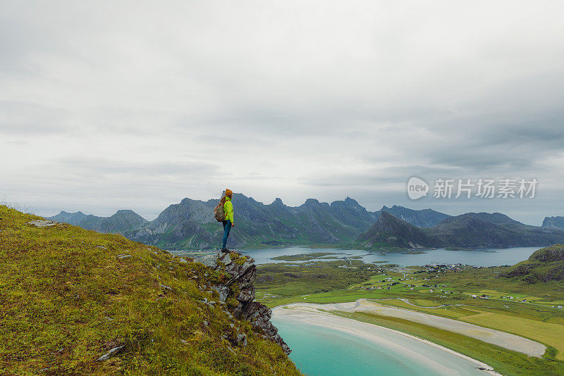 女性背包客从罗弗敦群岛顶部凝视着海洋和山脉的风景